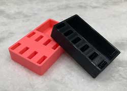 Two 3D printed USB stick holders, one pink and one black, on a marble counter.